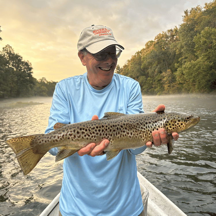 man holding a trout while summer fly fishing on the watauga river